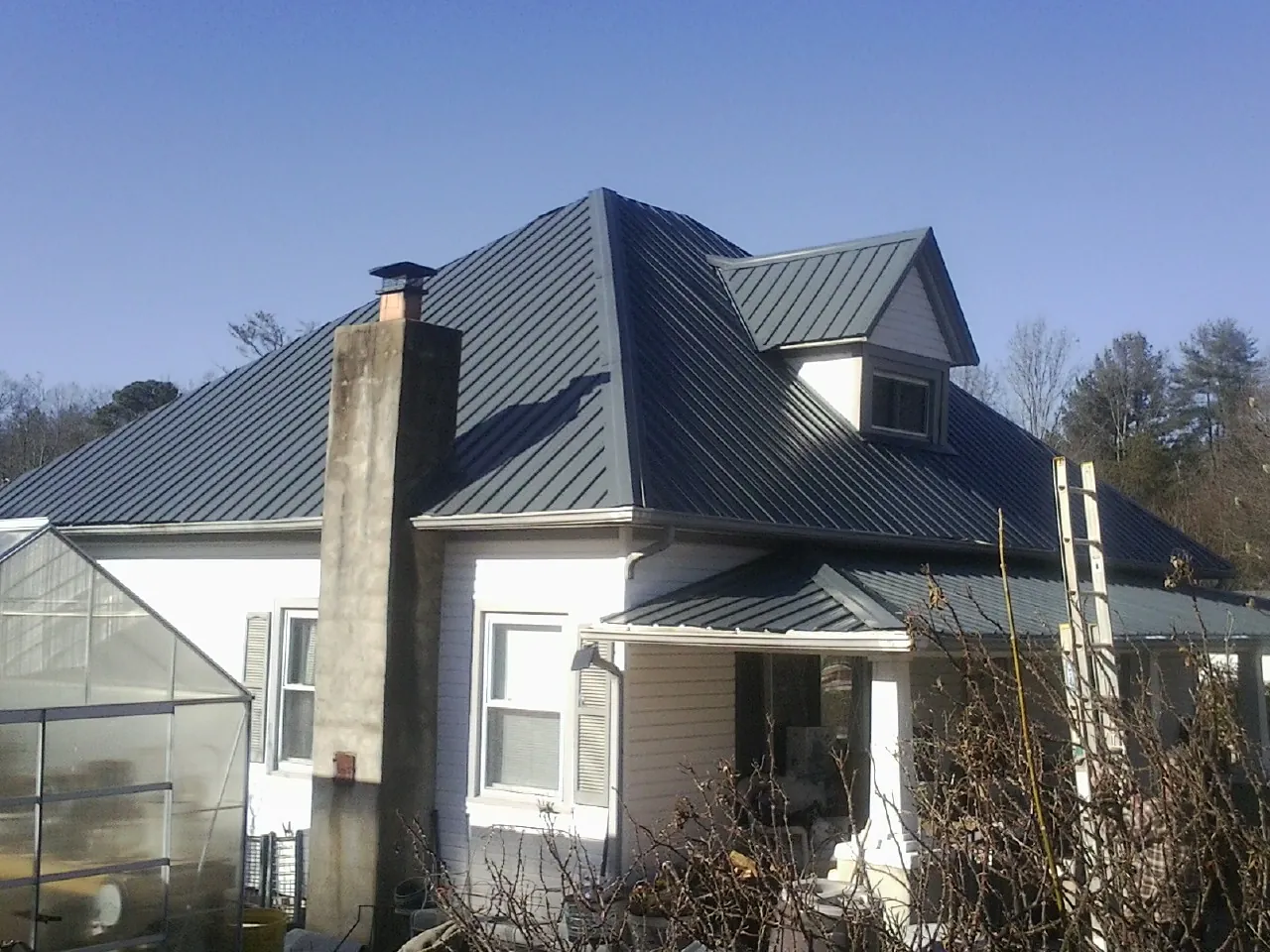 Dark blue standing seam metal roof on a white farmhouse with dormer — Slate & Tile Roof Repair by Roofing Brothers in Ryegate
