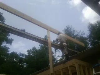 Carpenter setting a ridge beam over a new addition frame — Ice Dam Removal by Roofing Brothers in Ryegate