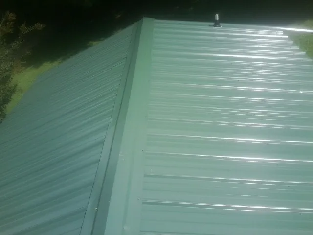 New green metal panels meeting at the ridge of a roof — Flat Roof Repair work by our crew in Ryegate