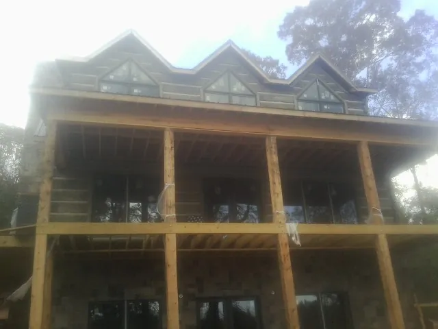 Dormers and porch framing on a large log home under construction — Roof Coating work by our crew in Ryegate