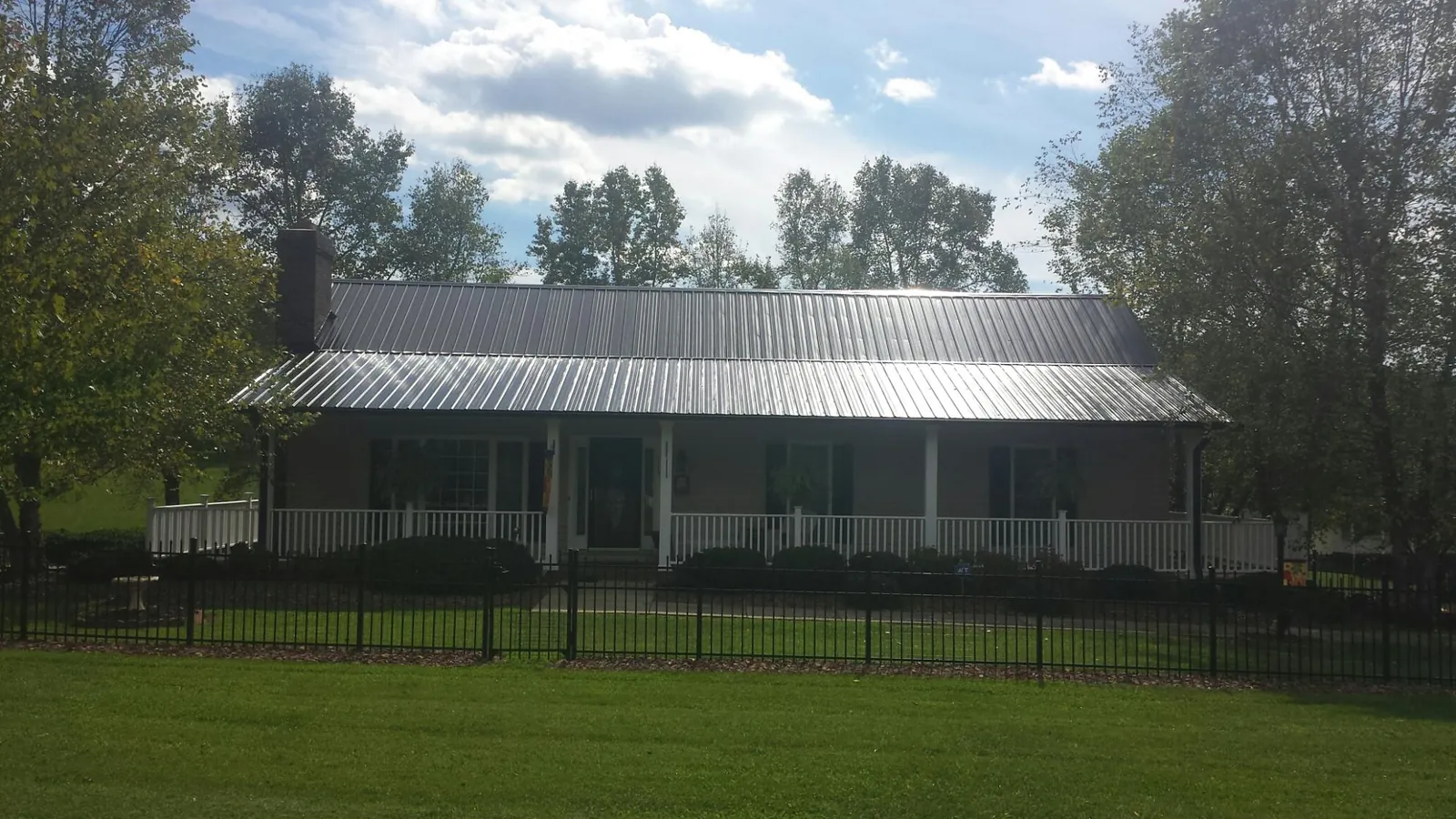 Gray metal roof on a brick ranch with a full width front porch — Gutter Guard Installation work by our crew in Ryegate