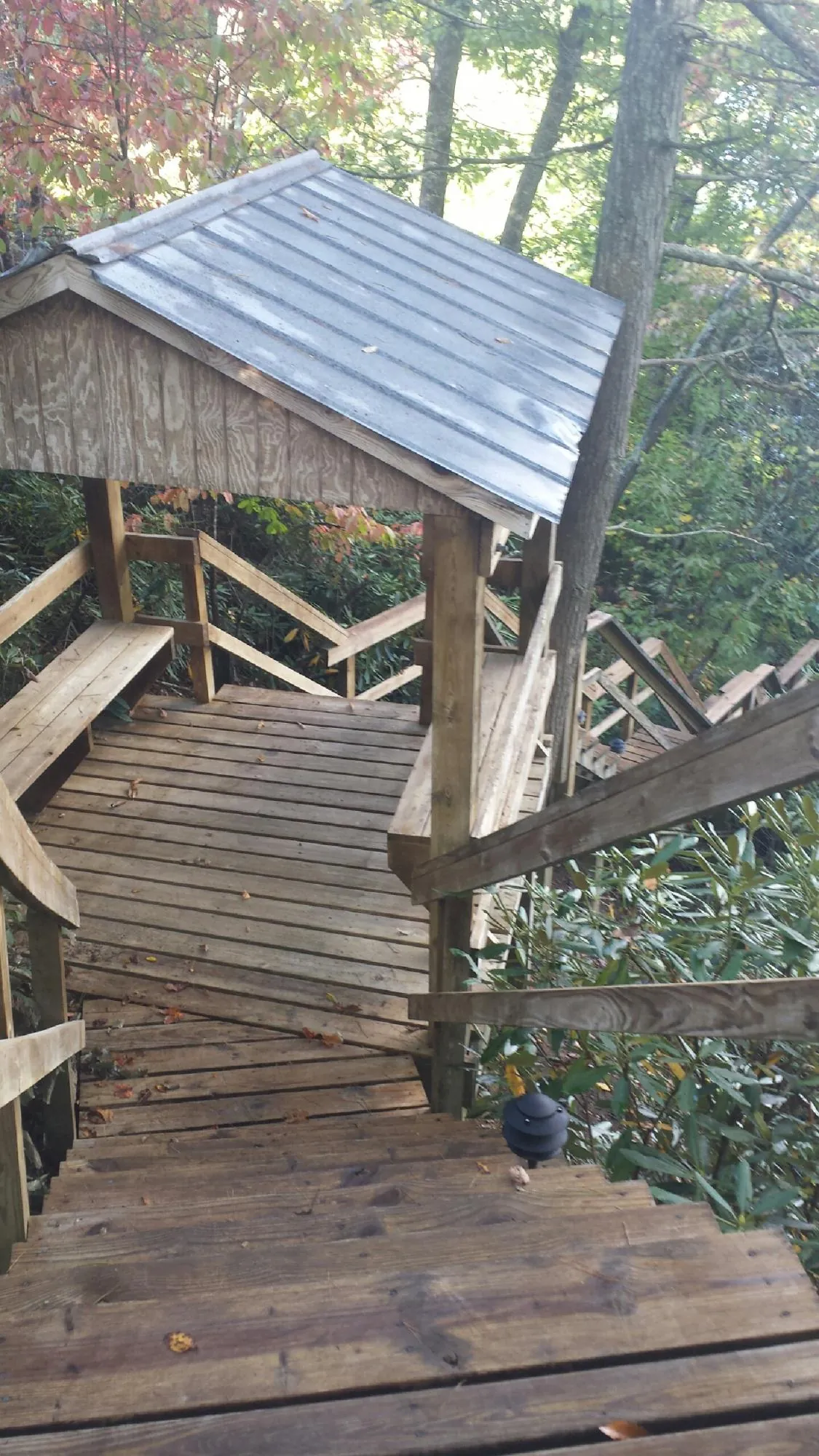 Metal roofed shelter over wooden steps on a wooded walkway — Skylight Repair & Installation work by our crew in Ryegate